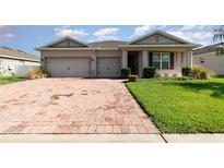 Charming single-story home with a brick driveway, well-manicured lawn, and a welcoming front entrance at 2249 Palmetum Loop, Apopka, FL 32712