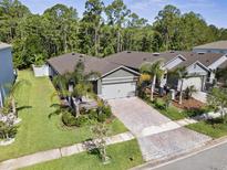 Aerial view of a well-maintained home with a brick driveway and lush landscaping surrounded by trees at 280 Caryota Ct, New Smyrna Beach, FL 32168