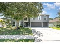 Charming two-story home featuring a three-car garage, mature landscaping, and a welcoming front entrance at 3063 Mandolin Dr, Kissimmee, FL 34744