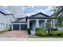 Charming two-story home featuring a brick driveway, lush landscaping, and a covered entryway with elegant columns at 9917 Summerlake Groves St, Winter Garden, FL 34787