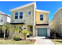 Modern two-story home featuring a mint-green garage door, complemented by small palm trees and fresh landscaping at 1077 Leader St, Davenport, FL 33896