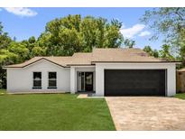 Charming single-story home features a lush lawn, modern design, and a spacious two-car garage at 1301 Paradise Ln, Winter Park, FL 32792