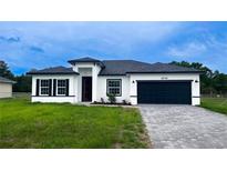 Charming single-story home featuring a dark garage door, modern architecture, and a well-maintained lawn at 16734 Sw 18Th Avenue Rd, Ocala, FL 34473