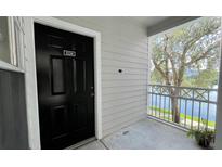 A black front door and a lovely view of the serene lake and lush greenery from the entryway balcony at 2314 Mid Town Ter # 1126, Orlando, FL 32839