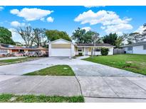 Charming one-story home featuring an attached garage, lush lawn, and a concrete driveway at 2809 Pioneer Rd, Orlando, FL 32808