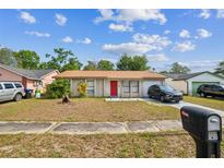 Charming single-story home with a red front door, a cozy front yard, and driveway at 3711 Shady Grove Cir, Orlando, FL 32810