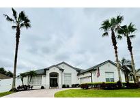 Charming single-story home with landscaped front yard, circular driveway, and decorative palm trees at 4412 Conroy Club Dr, Orlando, FL 32835