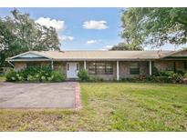 Charming one-story brick house with mature landscaping, spacious lawn, and a concrete driveway and walkway at 949 Shadow Oaks Rd, Kissimmee, FL 34744