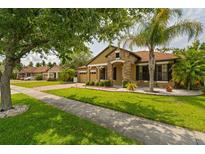 Charming single Gathering home featuring stone accents, manicured lawn, and mature trees at 9852 Caroline Park Dr, Orlando, FL 32832
