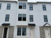 New construction townhome exterior featuring white siding, modern windows, and individual entryways at 15089 Grove Lake Dr, Winter Garden, FL 34787