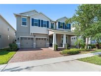 Two-story home with a brick driveway, 2-car garage and manicured lawn and blue shutters at 15420 Southern Martin St, Winter Garden, FL 34787