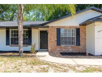 Charming home exterior featuring a brick facade, black shutters, and a well-maintained lawn at 18 Palmira Rd, Debary, FL 32713