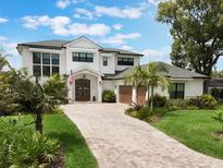 Stunning two-story home featuring a brick driveway, lush landscaping, and a welcoming front entrance at 1891 Lake Spier Dr, Winter Park, FL 32789