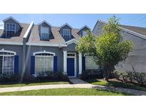 Charming two-story townhome with blue shutters, a well-maintained lawn, and mature tree at 2157 Island Walk Dr, Orlando, FL 32824