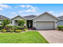 Charming single-story home with lush landscaping, manicured lawn, and a brick driveway at 4051 Prairie Reserve Blvd, Orlando, FL 32824