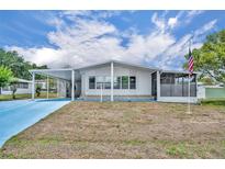 Charming single-story home featuring a carport, screened porch, and a well-maintained lawn under a sunny sky at 750 Polo Park Blvd, Davenport, FL 33897