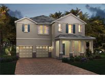 Two-story home featuring a brick paver driveway, a two-car garage, and lush landscaping at 11057 Hollow Bay Dr, Winter Garden, FL 34787
