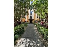 Beautifully landscaped walkway leading to the building entrance, surrounded by lush greenery and mature trees at 12527 Floridays Resort Dr # 506-E, Orlando, FL 32821