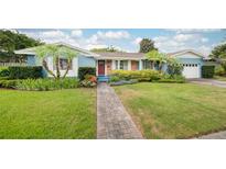 Charming blue home with well-manicured front yard, lush landscaping, and inviting brick walkway at 1516 Arthur St, Orlando, FL 32804