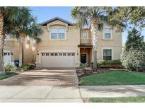 Charming two-story home with a brick driveway and a spacious two-car garage surrounded by lush landscaping and mature palm trees at 2186 Tripoli Ct, Kissimmee, FL 34747