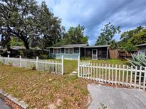 Charming single-story home featuring a quaint picket fence and an inviting screened-in porch at 245 S Rhodes St, Mount Dora, FL 32757