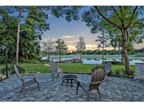 Paver patio with fire pit and seating overlooks a tranquil lake and dock with gazebo at 277 Sunrise Pt, Lake Mary, FL 32746
