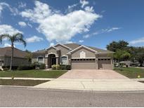 Charming single-story home featuring a three-car garage, landscaped yard, and paver driveway at 4906 Keaton Crest Dr, Orlando, FL 32837