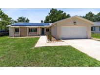 Charming single-story home with solar panels, a well-maintained lawn, and an attached two-car garage at 525 Southport Dr, Longwood, FL 32750