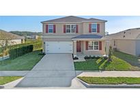 Charming two-story home featuring a two-car garage, landscaped lawn, and vibrant red shutters at 5896 Galloping Dr, Apopka, FL 32712
