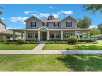 Charming two-story home featuring a spacious front porch, manicured lawn, and beautiful landscaping at 10100 Loblolly Pine Cir, Orlando, FL 32827