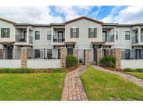 Inviting townhouse exterior with manicured lawn, brick pathway, gated entry, and private balconies at 109 Kenny Blvd, Haines City, FL 33844