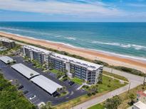Stunning aerial view of beachfront condos with direct beach access, covered parking and lush landscaping at 3100 Ocean Shore Blvd # 4030, Ormond Beach, FL 32176