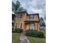 Charming two-story home with a well-manicured lawn and inviting entryway featuring a brick walkway and lush landscaping at 3500 Calabria Ave, Davenport, FL 33897