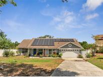 Charming single-story home with a well-manicured lawn, solar panels, and attached two-car garage at 6017 Brookhill Ct, Orlando, FL 32810