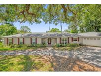 Charming single-story home with a mature landscaped front yard and red window shutters at 633 Balmoral Rd, Winter Park, FL 32789