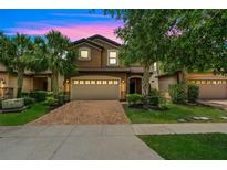 Charming home featuring a two-car garage, lush landscaping, and a brick driveway at 8989 Rhodes St, Kissimmee, FL 34747