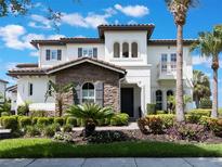 Elegant two-story home with stone accents, lush landscaping, and a well-maintained front yard on a sunny day at 14285 United Colonies Dr, Winter Garden, FL 34787