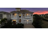 Elegant two-story home featuring a tile roof, balconies, and a paved driveway against a colorful twilight sky at 304 Muirfield Loop, Reunion, FL 34747