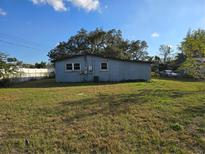 Home's backyard features a spacious lawn with an adjacent car parked alongside the building at 306 W Palm St, Davenport, FL 33837