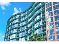 A modern high-rise condo building features curved architecture, glass balconies, and vibrant teal exterior paint at 322 E Central Blvd # 1612, Orlando, FL 32801