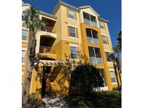 Condo building with yellow facade, wood shutters, multiple balconies, and lush green landscaping at 3338 Robert Trent Jones Dr # 30704, Orlando, FL 32835