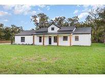 Charming white farmhouse-style home featuring a covered porch and verdant green lawn at 7195 Sw 125 Terrace Rd, Ocala, FL 34481