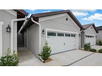 Exterior shows a one-car garage with a white garage door and manicured landscaping around the garage at 8560 Magnificent Ln, Groveland, FL 34736
