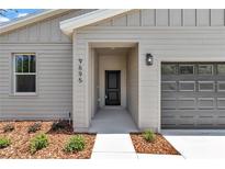 Charming single-Gathering home front entrance with a black front door and a gray garage door at 9695 Sw 125 Court Rd, Dunnellon, FL 34432