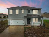 Two-story home featuring a gray exterior, a two-car garage, and a covered front porch at 979 Sun Burst Rd, Winter Haven, FL 33880