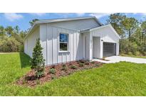 Charming single-story home features modern white siding, manicured landscaping, and a convenient attached garage at 12197 Sw 76 Ln, Dunnellon, FL 34432