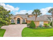 Inviting single-story home featuring a paved driveway, lush landscaping, and a striking arched entryway at 13524 Glynshel Dr, Winter Garden, FL 34787