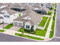 An aerial view of a pristine single-Gathering home featuring a manicured lawn and a spacious two-car garage at 15161 Lake Bessie Loop, Winter Garden, FL 34787