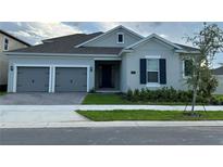 Charming single-story home with a two-car garage, manicured lawn, and traditional architectural details at 15161 Lake Bessie Loop, Winter Garden, FL 34787