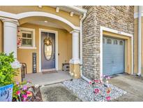 Inviting front porch with elegant columns, stone accents, and a charming floral wreath on the door at 2039 Beachberry Ln, Oviedo, FL 32765